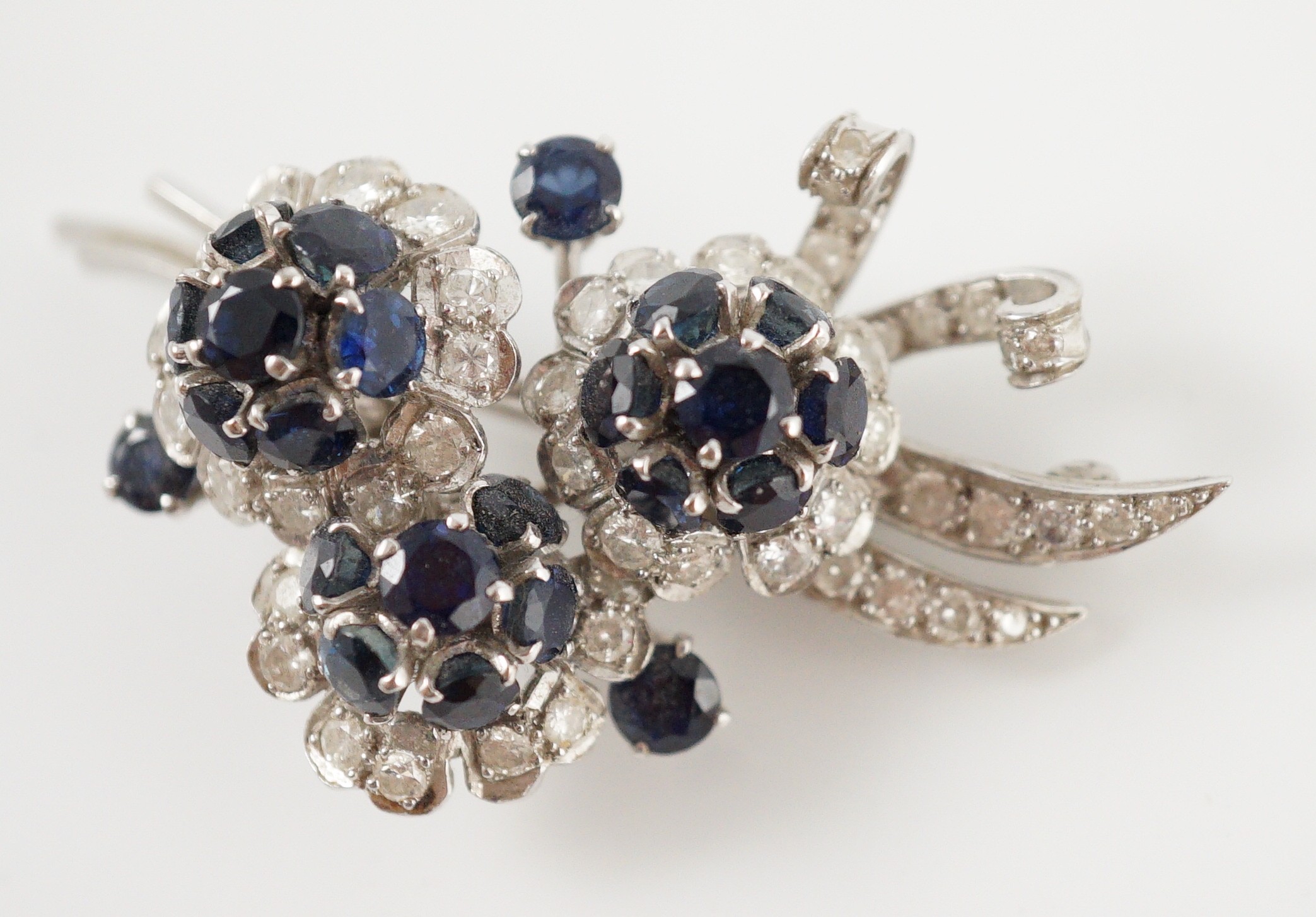 A white gold, sapphire and diamond cluster set floral spray brooch